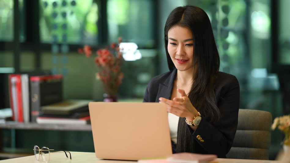 Woman in office attire working on a laptop